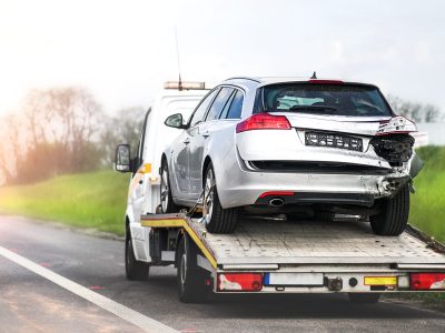 Loading broken car on a tow truck. Damage vehicle after crash accident on the highway road.